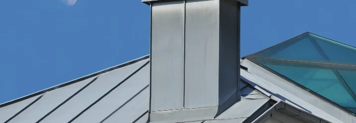Metallkamin auf einem Dach mit Mond im Hintergrund